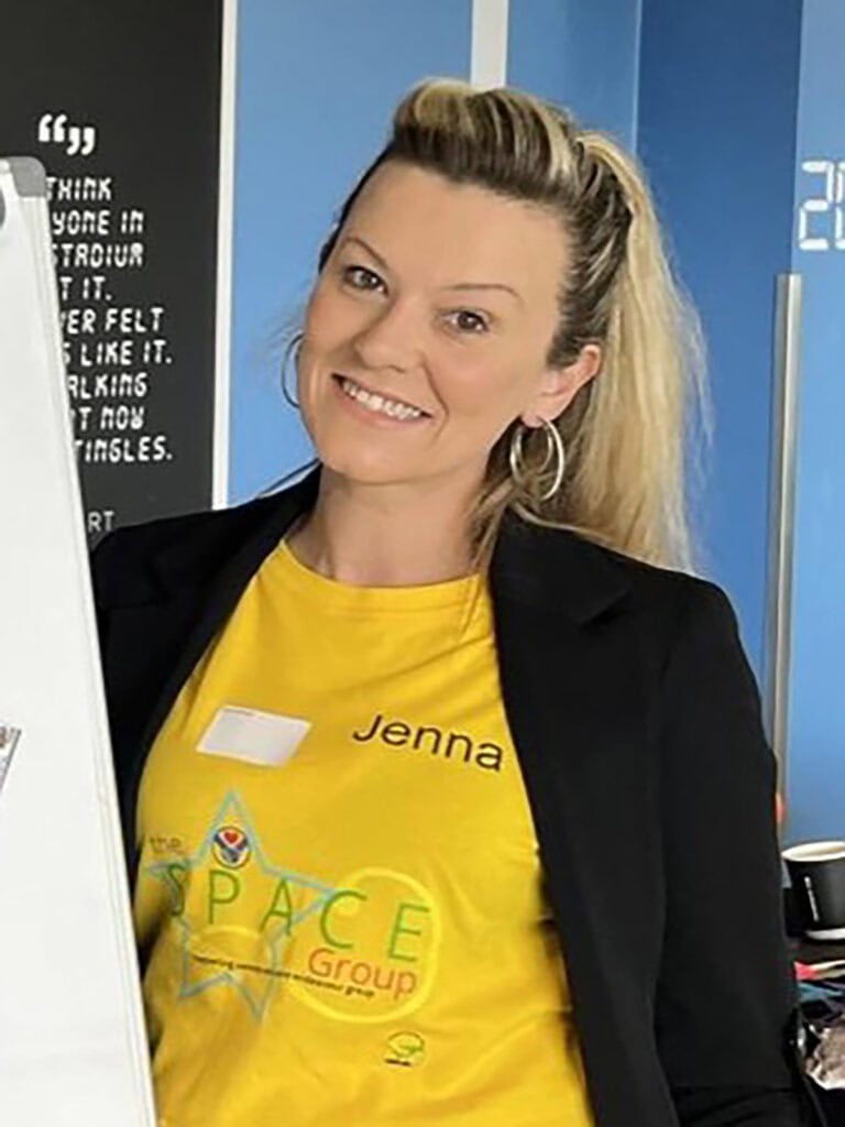 A portrait photo of Jenna Hillyard wearing a yellow t shirt that reads 'SPACE group'.