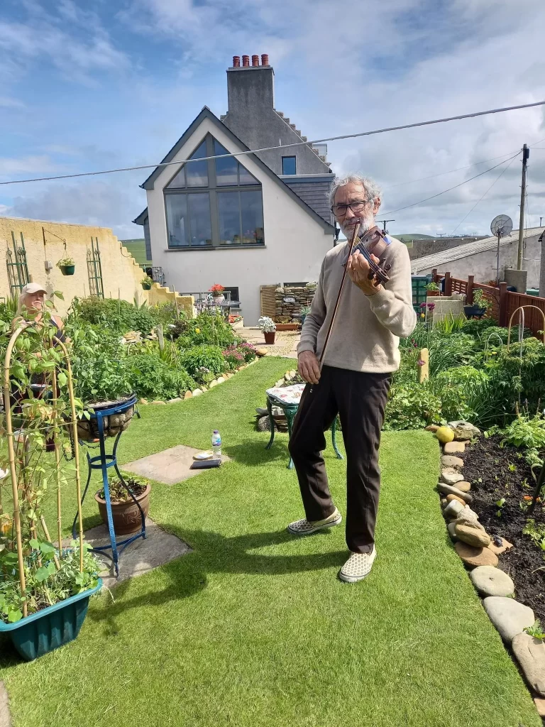 Volunteer Robin plays the fiddle in his garden.