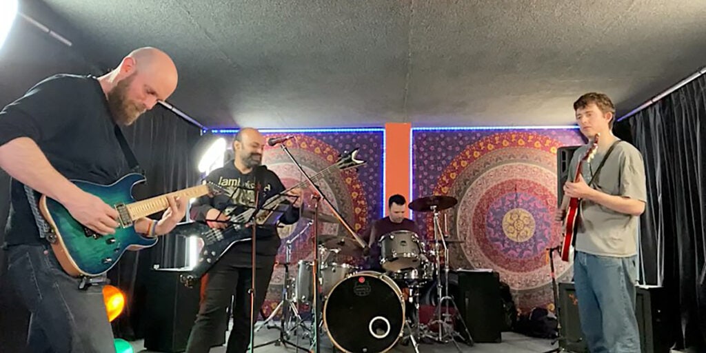 Two guitarists, a bassist and a drummer from the HEUristics playing in a practise room.