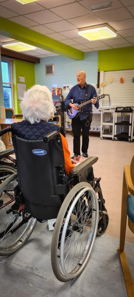 Musician preforming to residents playing guitar