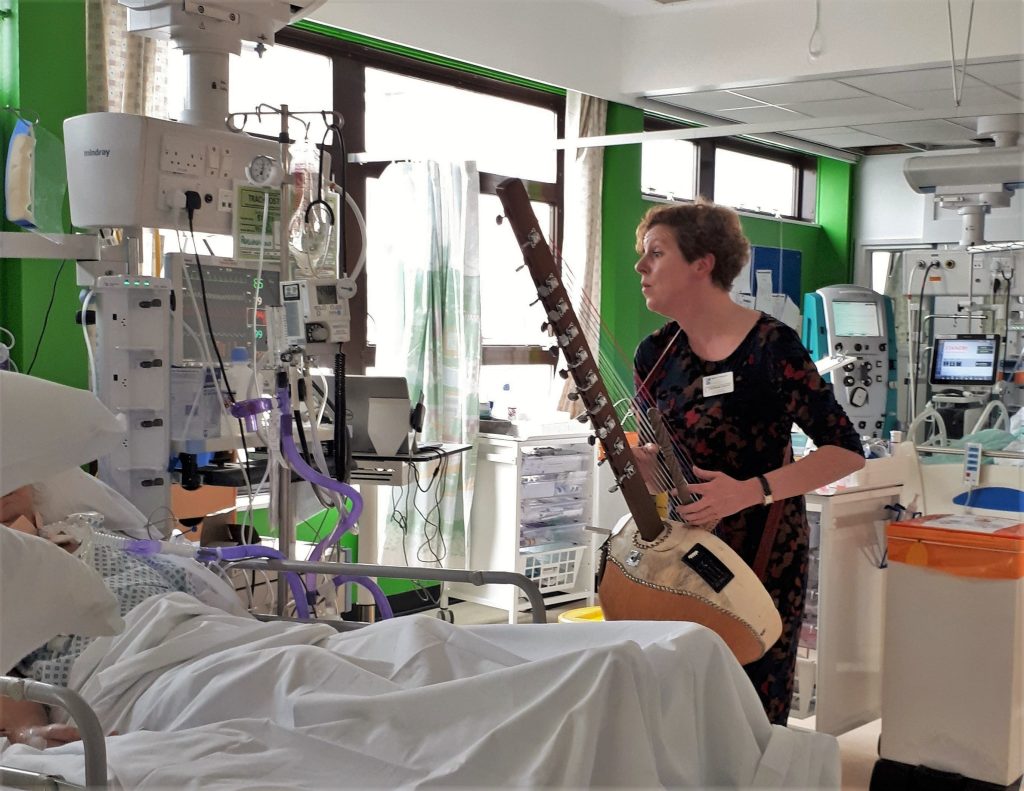 Musician playing a kora at the bedside of a patient in intensive care during a Music in Hospitals & Care session.