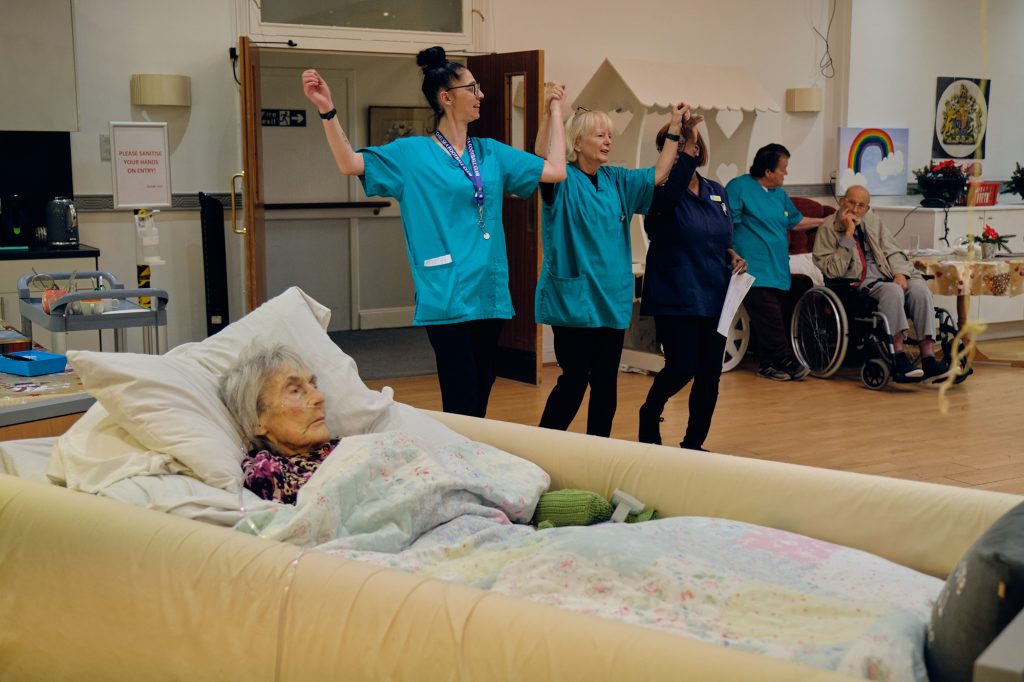 Care home staff dancing together while residents watch and enjoy a live Music in Hospitals & Care session.