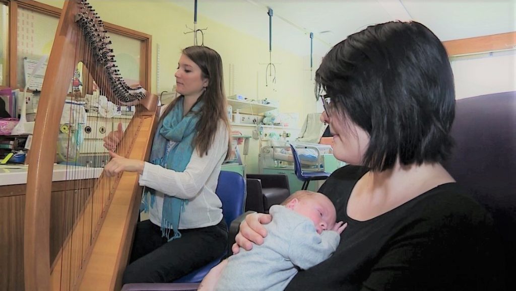 Harpist performing in a neonatal unit for a mother holding her baby during a Music in Hospitals & Care session.