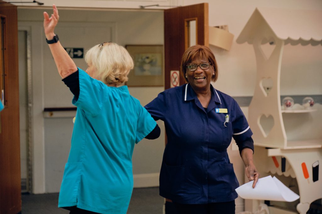 Two carers dancing together during a live music session at St David’s care home organised by Music in Hospitals & Care