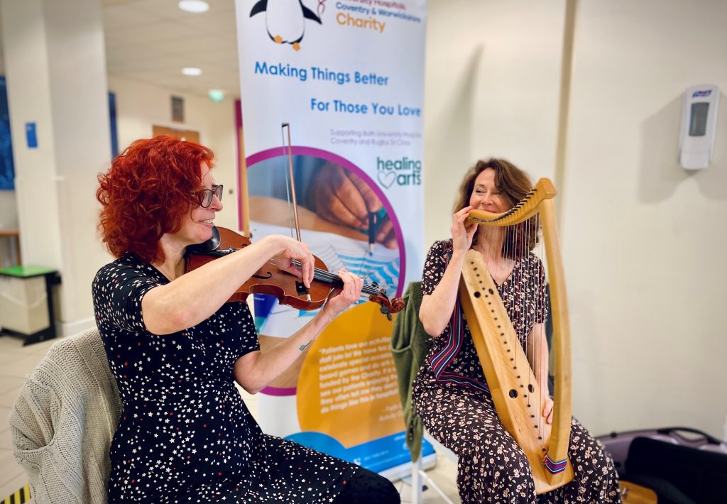 Two musicians performing with a violin and a small harp during a Healing Arts session, creating a joyful and calming atmosphere.